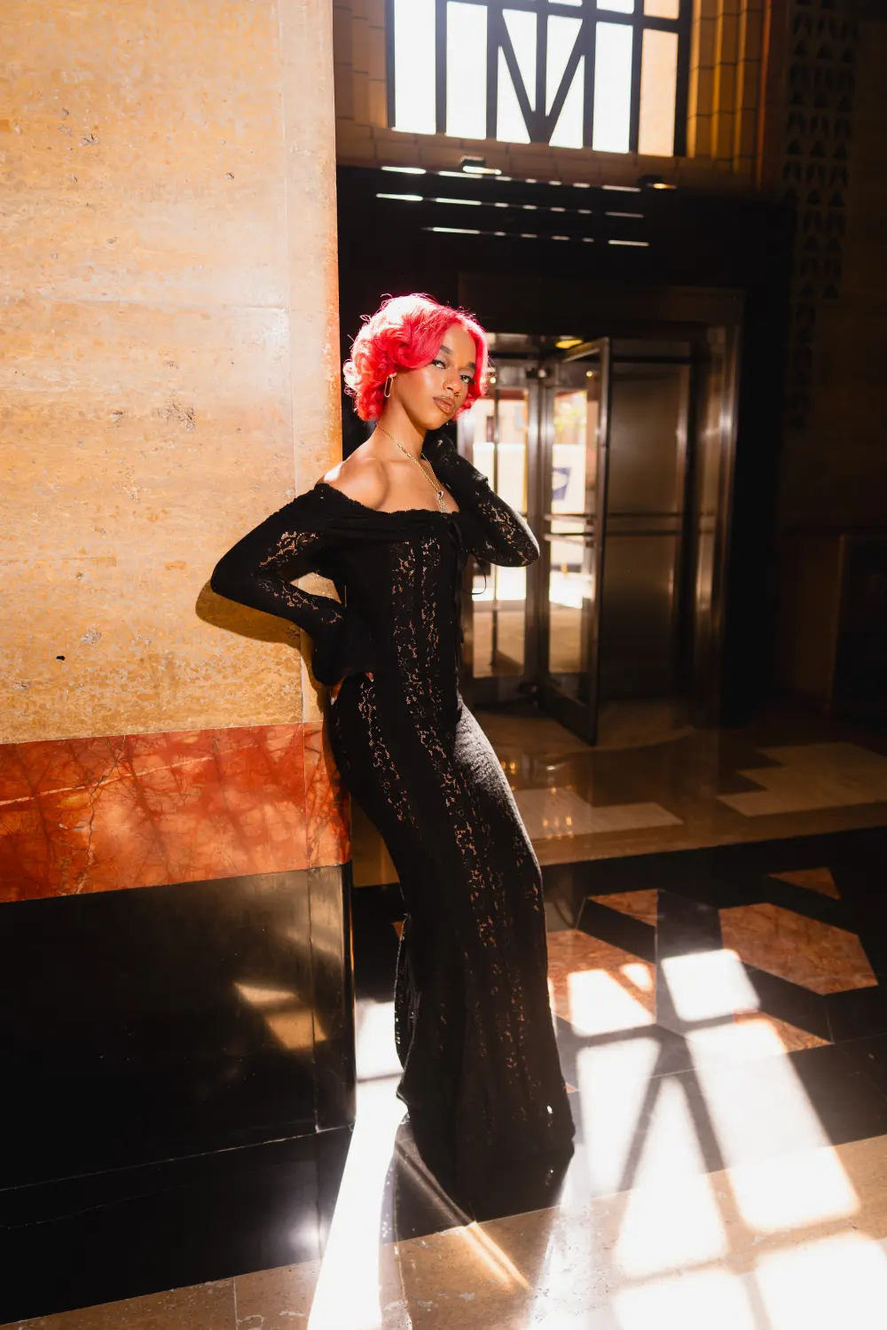 Woman in a black lace gown standing in sunlight in the Guardian Building lobby