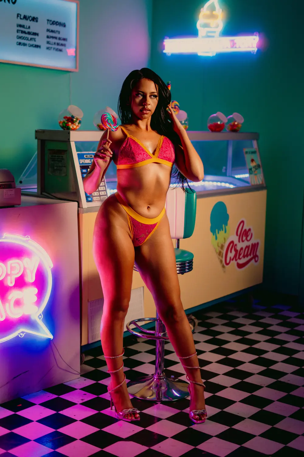 Woman in a pink and orange bikini posing in front of an ice cream shop counter